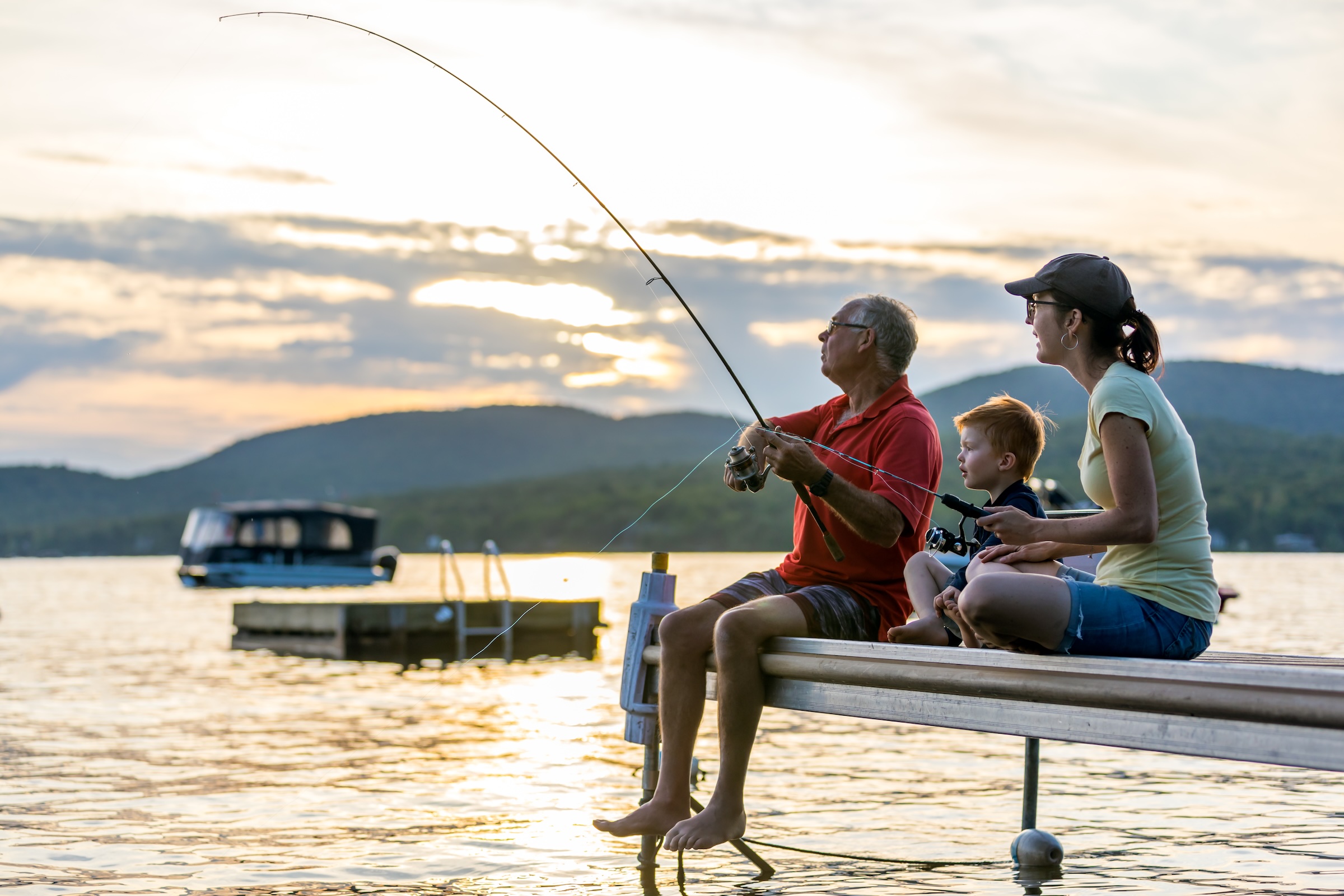 Famille pêchant ensemble depuis un quai sur un lac au Québec pendant un séjour en chalet.