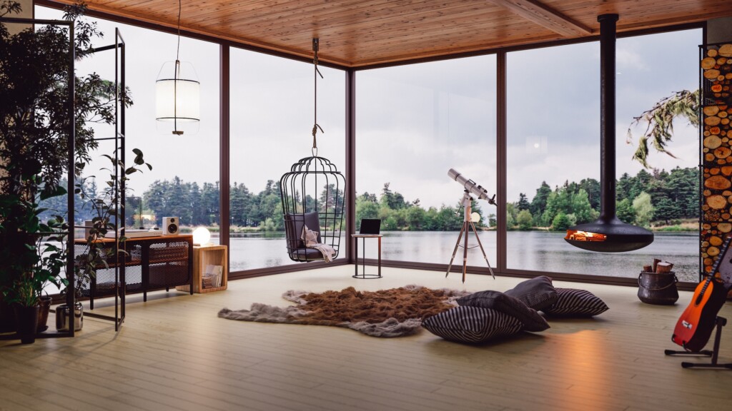 alon lumineux d’un chalet au bord d’un lac au Québec avec grandes fenêtres, foyer suspendu et vue sur l’eau.