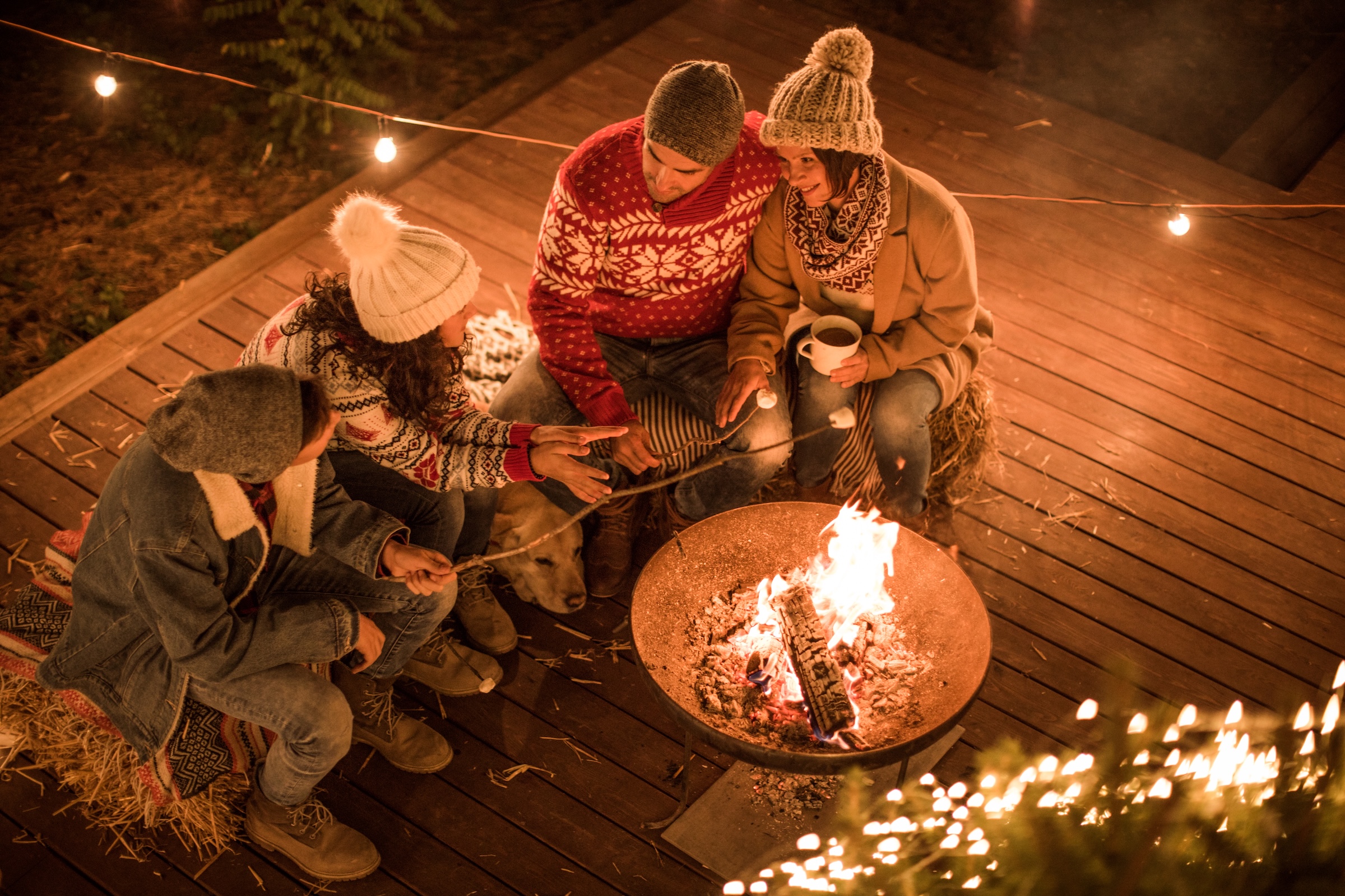 Famille réunie autour d’un feu extérieur sur la terrasse d’un chalet au Québec.