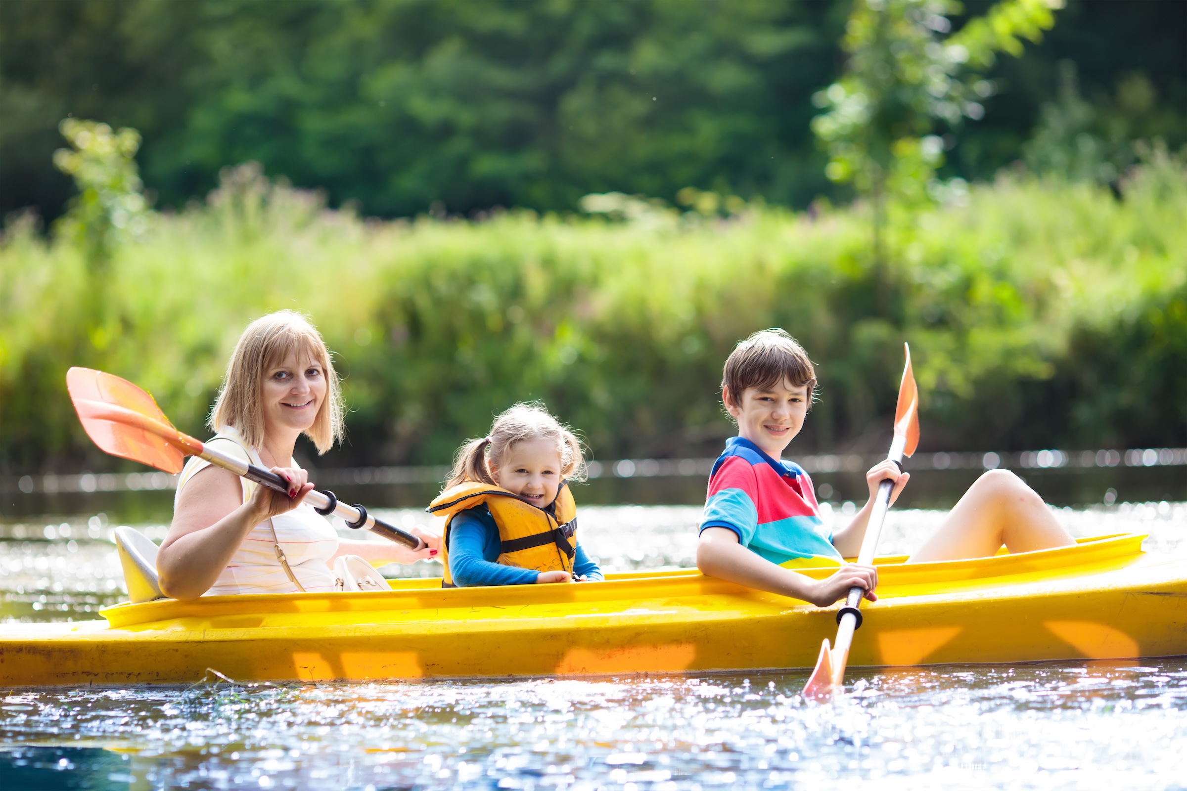 Famille faisant du kayak sur un lac pendant un séjour en chalet au Québec.
