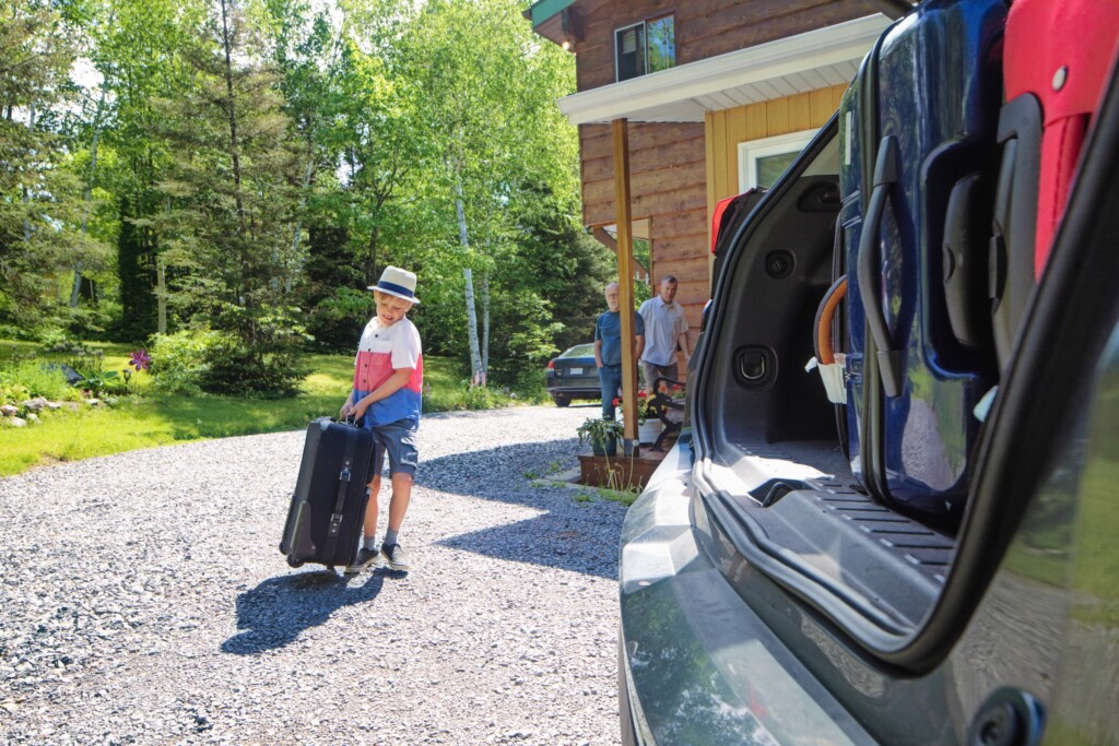 Famille arrivant à un chalet en Ontario avec des bagages pour un séjour de fin de semaine